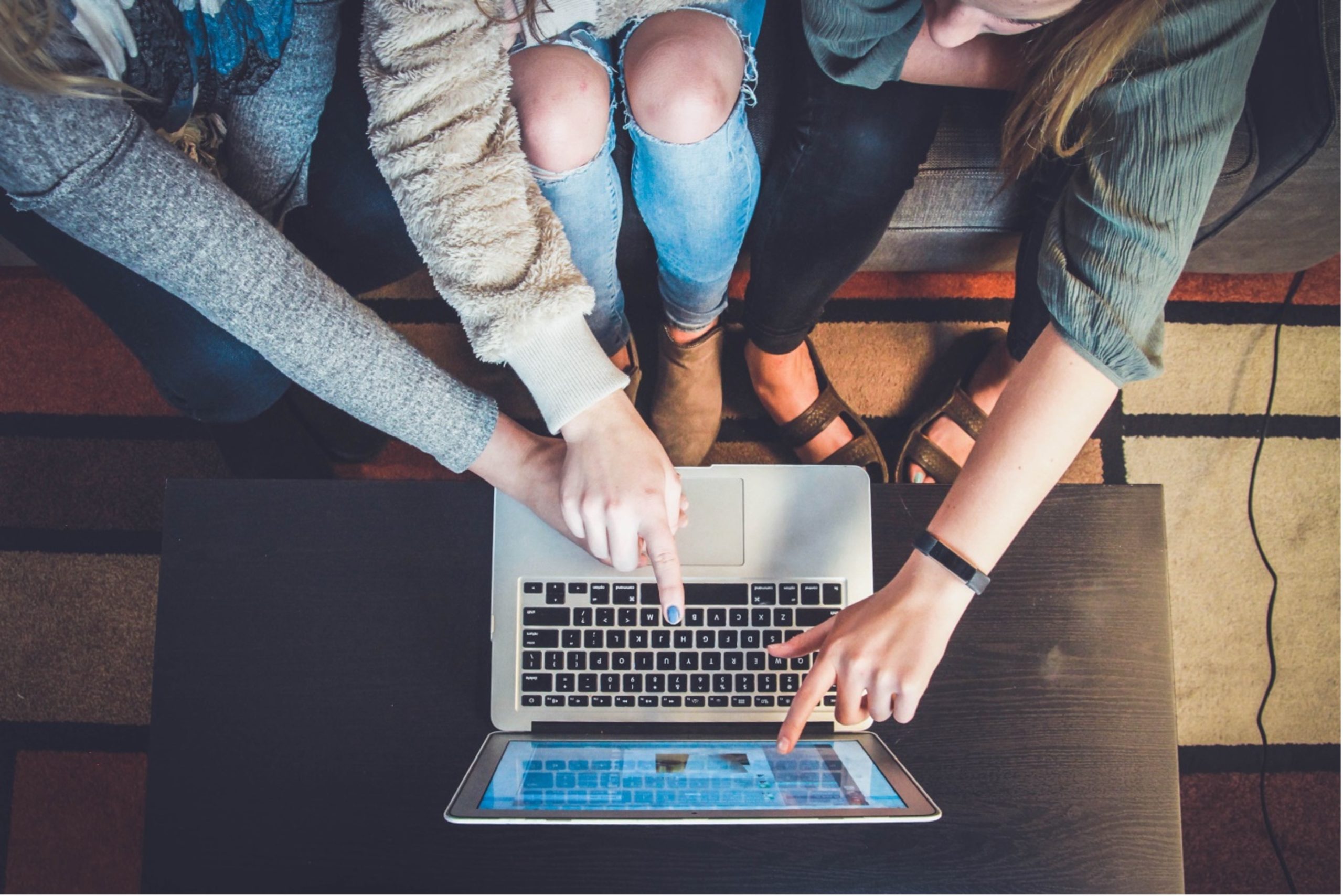 3 girls pointing at laptop